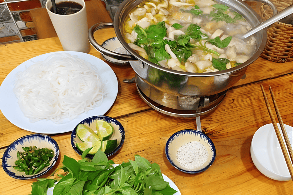 B&ecirc;n cạnh nồi lẩu l&agrave; đĩa rau xanh tươi, nấm v&agrave; b&uacute;n, sẵn s&agrave;ng cho một bữa ăn ấm c&uacute;ng v&agrave; tr&ograve;n vị (Nguồn: Fanpage Lẩu g&agrave; l&aacute; &eacute; 39)